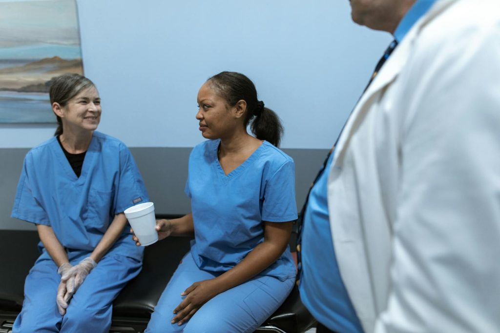 Two nurses chatting while one holds a drink in a medical office