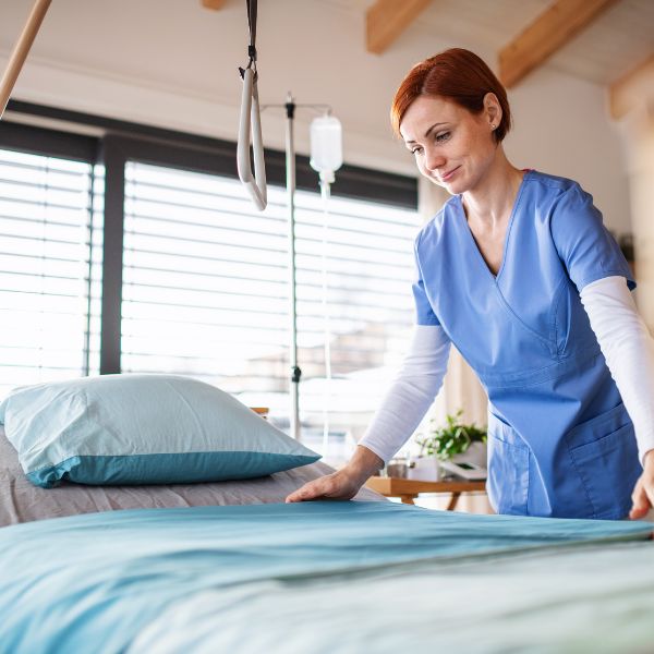 A nurse fixing a patients bed