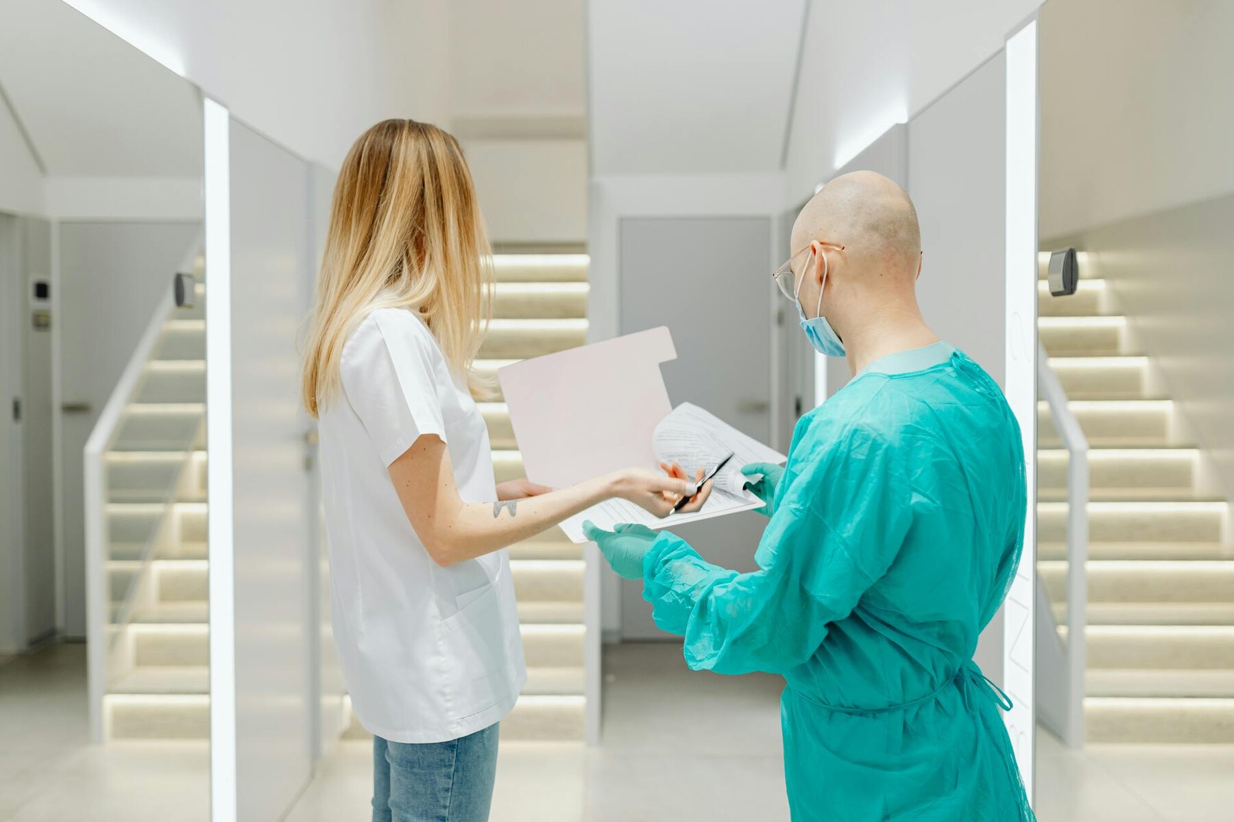 Healthcare workers discussing patient records in a bright hallway