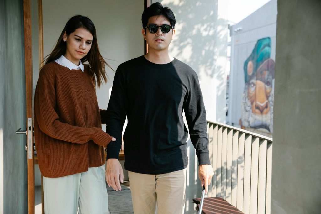 A woman assisting a blind man walking