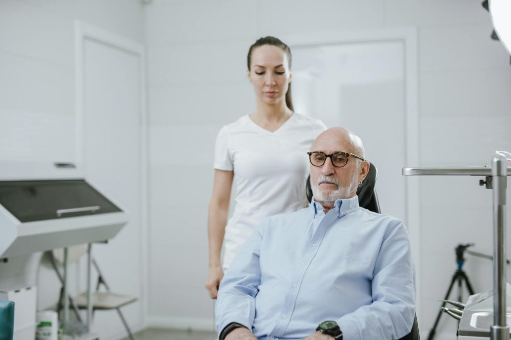 A healthcare worker helping an elderly man with a medical procedure