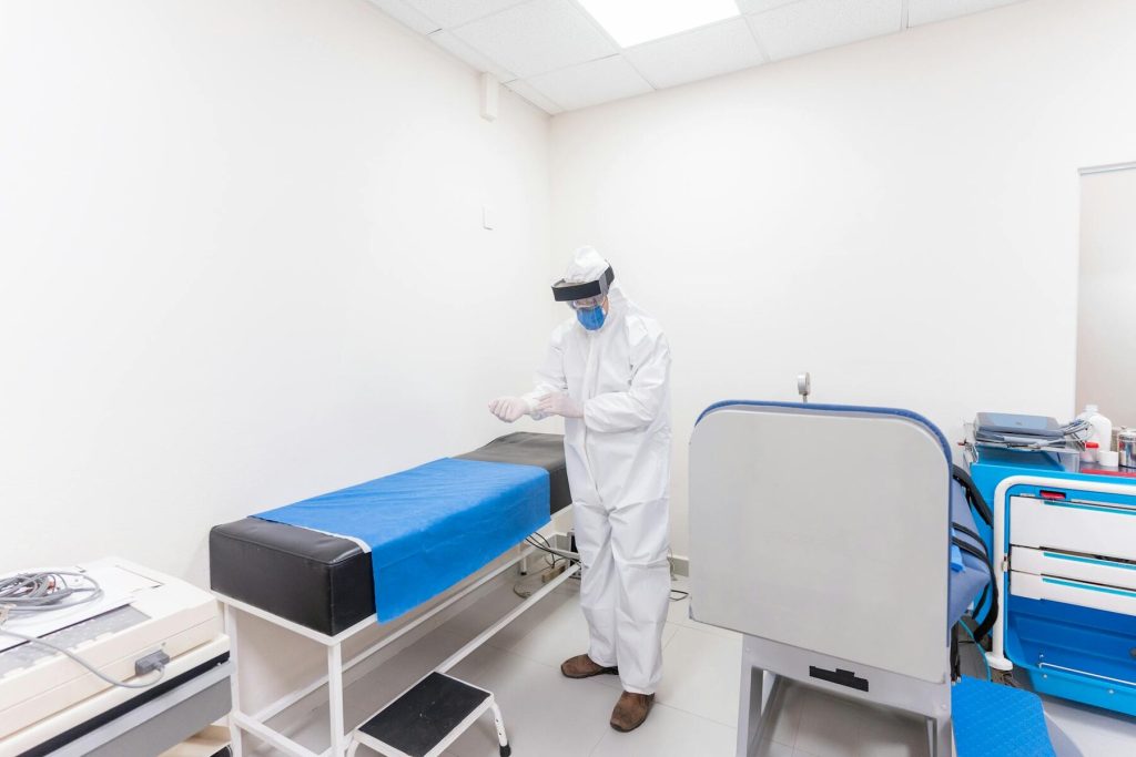 A healthcare worker in protective gear preparing a medical area